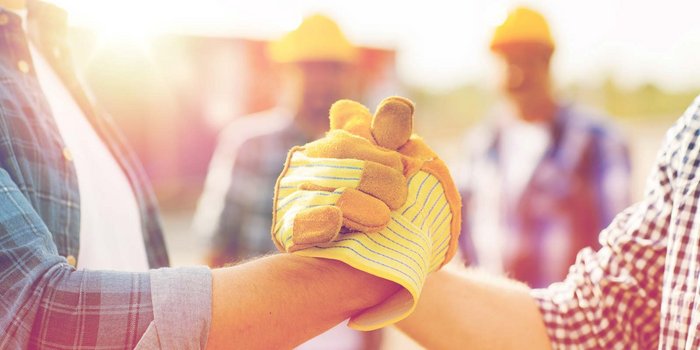 Zwei Männerhände mit Handschuhe die sich die Hand geben